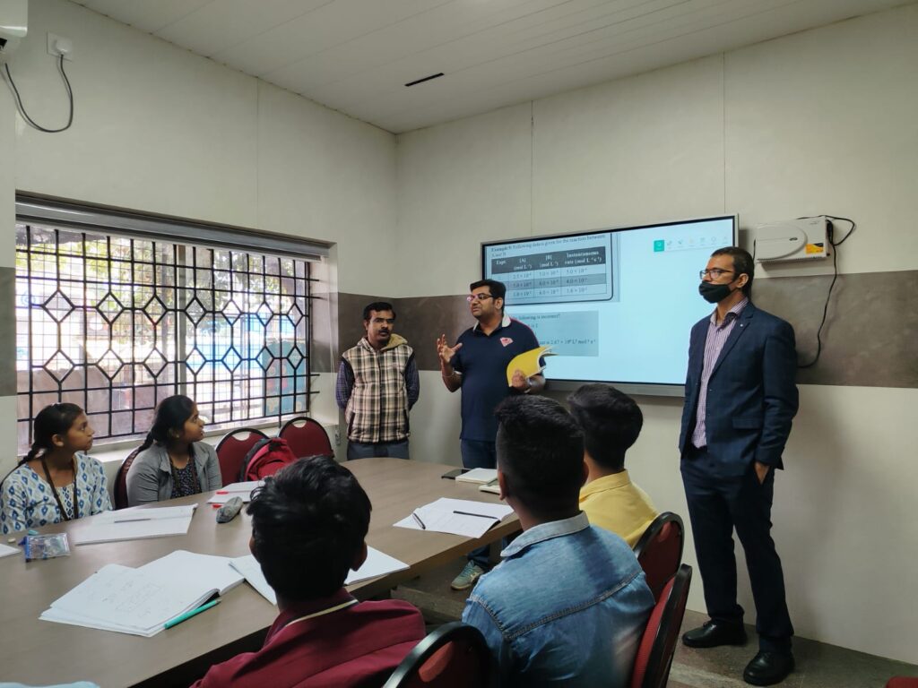 Faculty member presenting to students seated around a classroom table